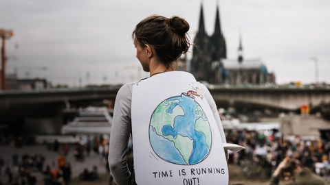 Junge Frau mit Demoplakat auf einer Klimademonstration in Kölln