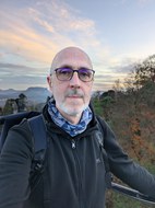 Mann mit Brille, weißem Bart und Rucksack, Natur im Hintergrund