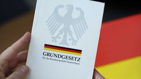 Das Grundgesetz mit einer Flagge im Hintergrund