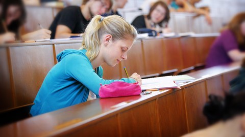 Studentin schreibt eine Prüfung im Hörsaal