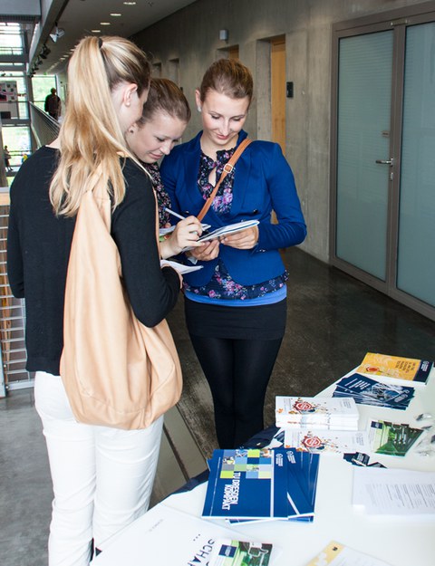 Die Besucherinnen am Stand des Bereichs Geistes- und Sozialwissenschaften sind mit der Lösung der Gewinnspielfragen beschäftigt.