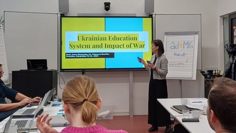 Menschen in einem Seminarraum. Auf der digitalen Tafel steht "Ukrainian Education System and Impact of War"" 