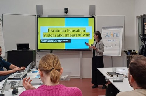 Menschen in einem Seminarraum. Auf der digitalen Tafel steht "Ukrainian Education System and Impact of War"" 