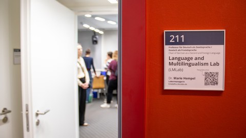 Blicks ins LMLab durch die Tür, rechts eine rote Wand mit Türschild