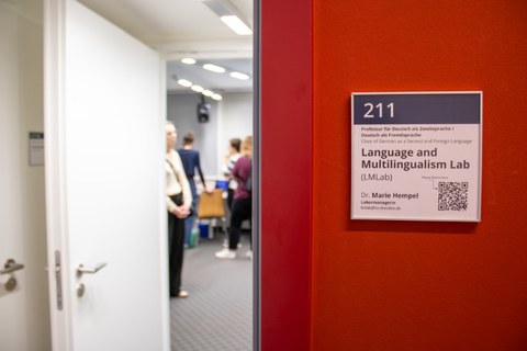 Blicks ins LMLab durch die Tür, rechts eine rote Wand mit Türschild