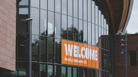 Gebäude mit Welcome at Warwick Plakat im Fenster