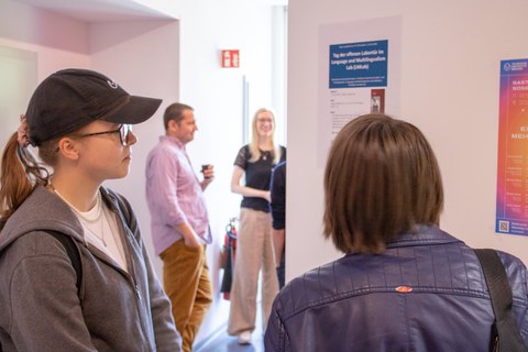 Menschen im Gang unterhalten sich und schauen Poster an