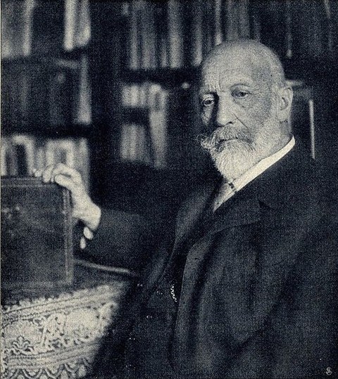 Zu sehen ist Carl Justi im Jahre 1906 in schwarz weiß vor einem Bücherregal.