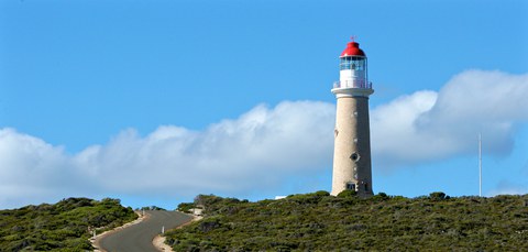 Zu sehen ist, ein weißer Leuchtturm mit rotem Dach auf einem Hügel.