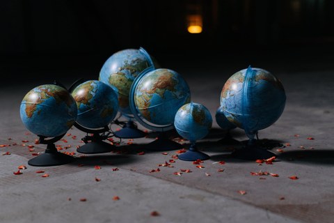 Zu sehen sind sieben Globen in unterschiedlicher Größe, welche auf einem grauen Fußboden stehen.