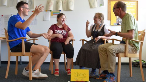 Auf dem Foto sitzen je zwei Männer und Frauen im Halbkreis auf Stühlen und diskutieren.