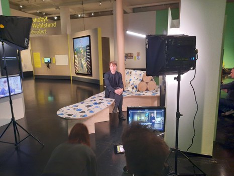 Lucas von Ramin beim TUDiSC Drehtag. Von Ramin sitzt im Gespräch und wir sehen die Kamerabildschirmsicht im Vordergrund. 