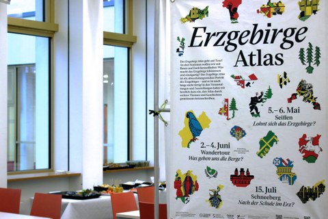 Großes Plakat, auf dem Erzgebirgeatlas steht und verschiedene Wappen und kommunale Abrisse dargestellt sind