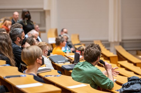 Menschen in einem Vorlesungssaal, die Fragen stellen