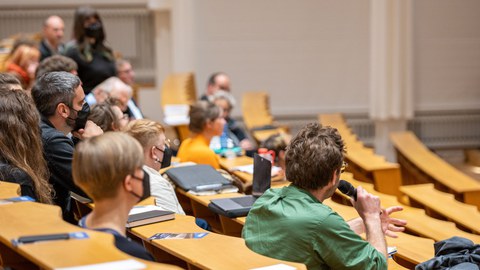 Menschen in einem Vorlesungssaal, die Fragen stellen