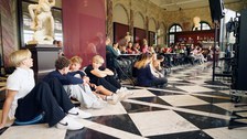 Gäste sitzen an Tischen und auf dem Boden im Café Algarotti im Semperbau.