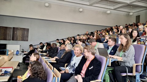 A conference room with many people looking at a stage