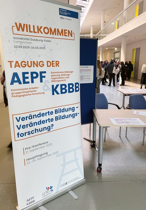 Im Foyer eines Unigebäudes steht ein Tagungsbanner der AEPF 2025 "Veränderte Bildung - Veränderte Bildungsforschung?"