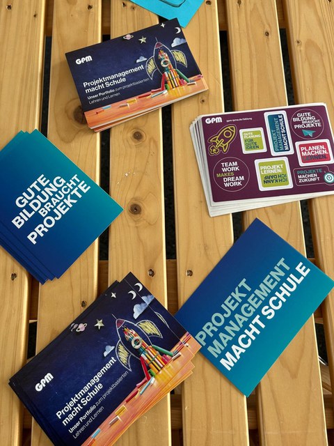 Flyer mit dem Motto "Gute Bildung braucht Projekte" liegen auf einem Tisch aus hellem Holz