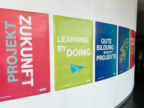 Eine Plakatwand mit den typographischen Motiven Zukunft, Learning by doing, Gute Bildung braucht Projekte! führt in einen Gang