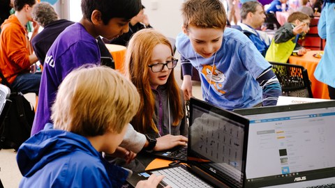 Kinder schauen beim Workshop zum Programmieren mit Scratch gemeinsam auf einen Laptop-Bildschirm.
