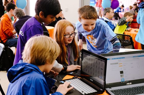 Kinder schauen beim Workshop zum Programmieren mit Scratch gemeinsam auf einen Laptop-Bildschirm.