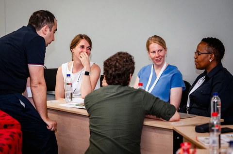 Fünf Personen sitzen um einen Konferenztisch und diskutieren.