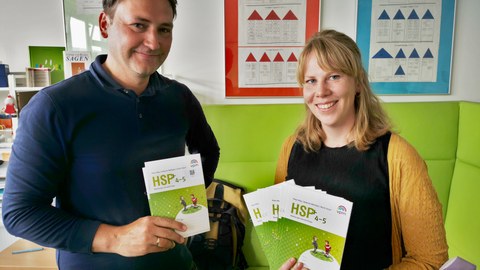 Die wissenschaftlichen Mitarbeiter:innen Dr. Matthias Ritter und Hannah Barthels freuen sich über die Hefte der Hamburger Schreibprobe.
