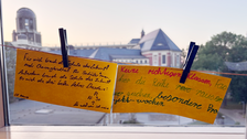 Zwei gelbe Zettel auf einer Wäscheleine mit handschriftlichen Antworten auf die Frage "Wie sieht für dich die Schule der Zukunft aus?"