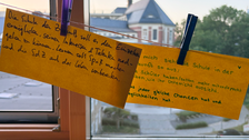 Zwei gelbe Zettel auf einer Wäscheleine mit handschriftlichen Antworten auf die Frage "Wie sieht für dich die Schule der Zukunft aus?"