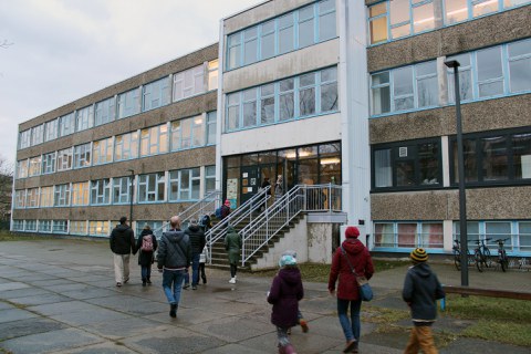 Viele Personen betreten über eine Treppe in den DDR-Schulbau der Universitätsschule Dresden.