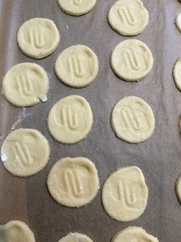 runde Kekse mit dem Logo der Universitätsschule Dresden liegen auf dem Backblech