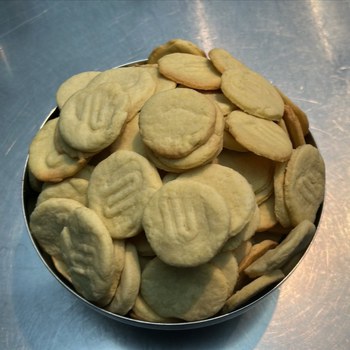 runde Kekse mit dem Logo der Universitätsschule Dresden liegen ain einer Keksdose