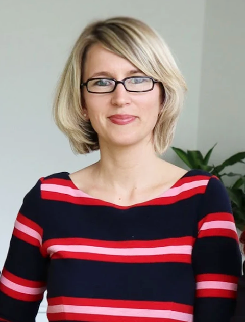 Portrait Maxi Heß, Schulleiterin der Universitätsschule Dresden, eine blonde Frau im dunkelblau und rot quer gestreiften Oberteil mit Brille.