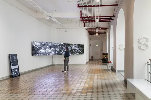 Ausstellungsansicht eines Raumes mit einem Kunstwerk auf einer LED-Wand. Davor steht eine Person und betrachtet die Arbeit.