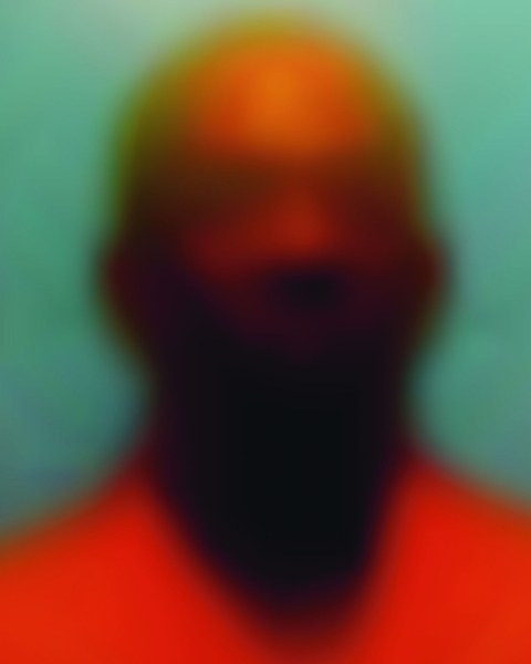 Verschwommenes Bild, man vermutet einen glatzköpfigen Mann mit rosa Hemd