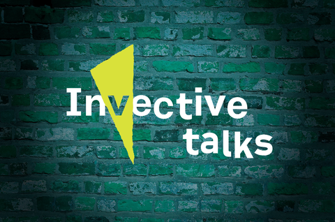 Logo "Invective Talks" im Stil des SFB-Logos, im Spotlight vor grüner Backsteinwand