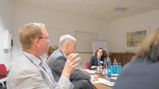 Menschen sitzen an einem Tisch und diskutieren miteinander