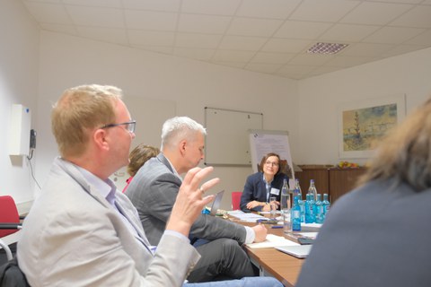 Menschen sitzen an einem Tisch und diskutieren miteinander