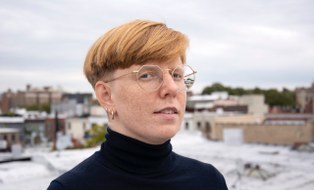 Portraitbild einer Person mit kurzen, roten Haaren und Brille