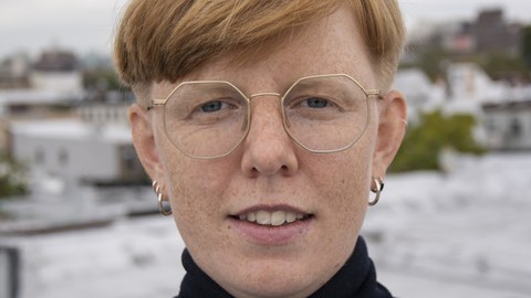 Portraitbild einer Person mit kurzen, roten Haaren und Brille