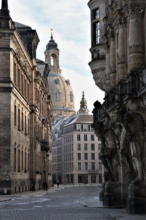 Zu sehen ist der Blick auf die Dresdner Frauenkirche aus einer Gasse heraus.