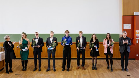 Die sieben ausgezeichneten Studierenden stehen nebeneinander vor eine Tafel. Links von ihnen steht die Rektorin Prof. Dr. Staudinger, ganz rechts der Prorektor Bildung, Prof. Dr, Kobel.