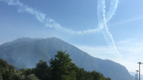 Kondensstreifenschleife über den Bergen von Trento.