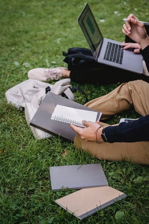 Personen mit Laptops sitzend auf Wiese