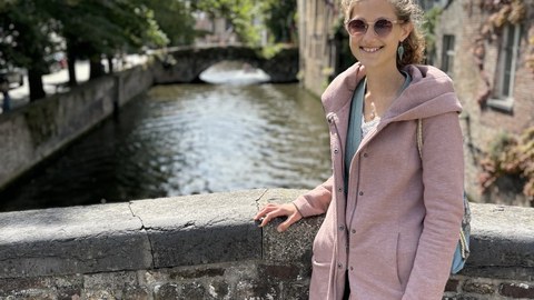 Miriam Stahlhacke auf einer Steinbrücke mit einem Fluss und einem Steinhaus im Hintergrund