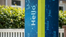 Foto einer Säule in TUD-Blau und Grün mit den Worten "Hello", "Hola", "Hei" und weiteren Sprachen