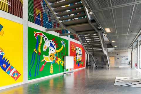 Eingangshalle des Hörsaalzentrums mit farbiger Wandbemalung und großer Treppe