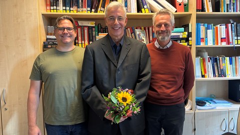 Das Bild zeigt Prof. Christian Leßmann, Stefan Robel und Prof. Alexander Kemnitz vor einer Bücherwand.