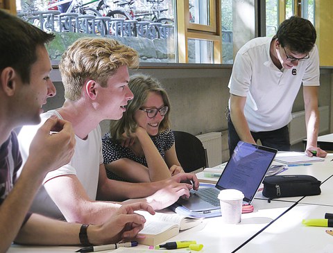Foto einer Gruppe von Studierenden, die auf den Bildschirm eines Laptops schauen